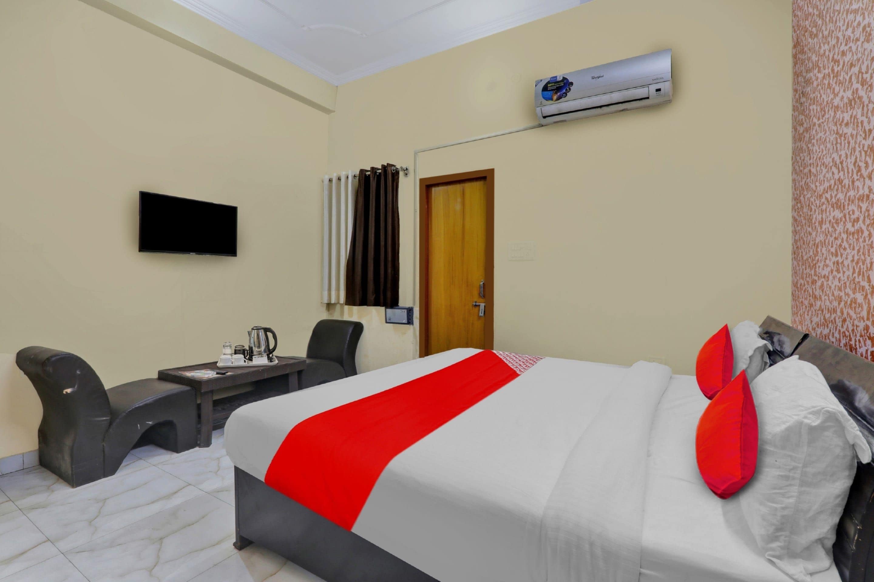 Habitación de hotel con cama, escritorio, silla, unidad de aire acondicionado y televisión.