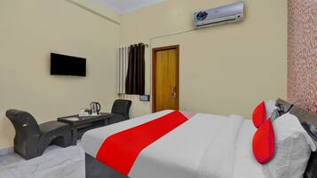 Habitación de hotel con cama, escritorio, silla, unidad de aire acondicionado y televisión.