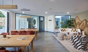 A modern hotel lobby with a dining area, seating, and a large window. - Bahia Sunrise Garden Golf Resort and Spa (La Cala de Mijas)