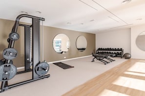 A modern gym with a weightlifting station, mirrors, a bench, dumbbells, and a yoga mat. - Bahia Sunrise Garden Golf Resort and Spa (La Cala de Mijas)