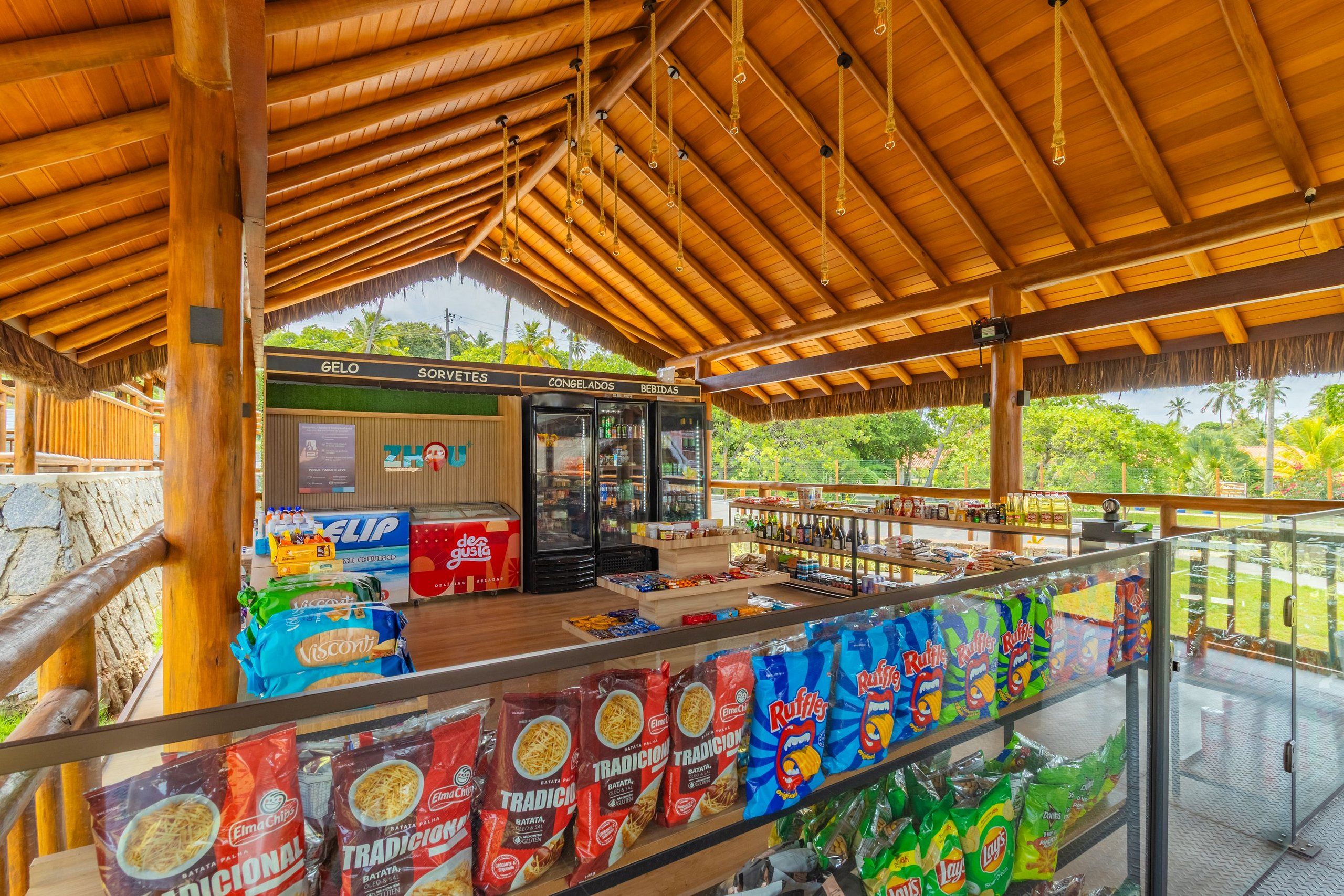 Un kiosque extérieur abrité, proposant une variété de collations et de boissons, notamment des sachets de chips et des boissons en bouteille.