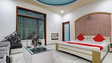 Une chambre d’hôtel avec un lit, une table basse en verre, un canapé et une fenêtre avec des rideaux.