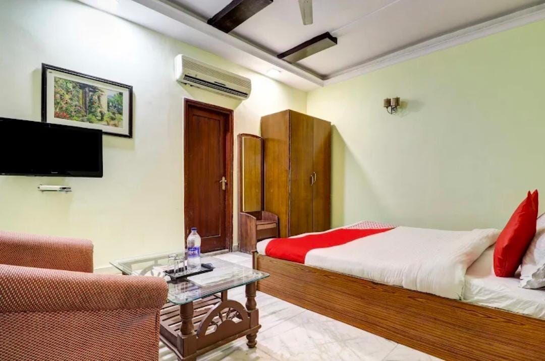 Una habitación de hotel con una cama, una mesa de centro de vidrio, una silla, un armario y un televisor.