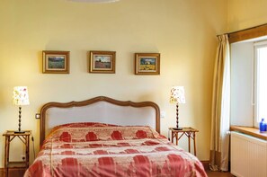 Een hotelkamer met een groot bed, twee nachtkastjes en drie ingelijste foto’s aan de muur.