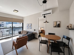 A modern living room with a sofa, chairs, a dining table, and a balcony with a view of buildings. - SETIN 1006 (São Paulo)