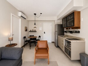 A compact living space with a kitchenette, dining area, and seating. - SETIN 1006 (São Paulo)