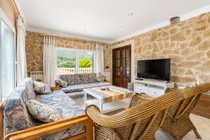 A living room with a sofa set, a television, and wicker chairs. - Vistabona, 5StarsHome Mallorca Villa (Capdepera)