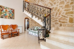 A staircase with a stone wall, a wooden bench, a sofa, and a painting on the wall. - Vistabona, 5StarsHome Mallorca Villa (Capdepera)