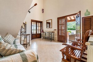 A cozy room with a sloped ceiling, a wooden chair, a table with a vase, and a view of greenery outside. - Vistabona, 5StarsHome Mallorca Villa (Capdepera)