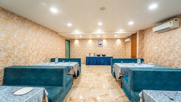 A conference room with marble flooring, teal upholstered seating, and tables set for meetings.