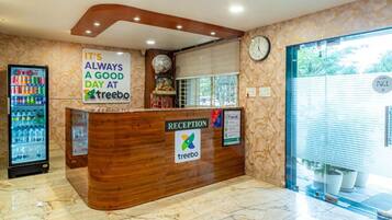 A reception desk with a clock, a sign saying 'It's always a good day at treebo,' and a Coca-Cola refrigerator.