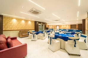 A conference room with round tables, white chairs with blue sashes, a red sofa, and a beige couch. - Treebo Ten Eleven Grand, Scheme 78 (Indore)