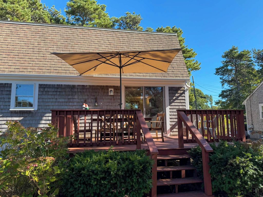 A covered outdoor deck with a wooden railing and a large umbrella.