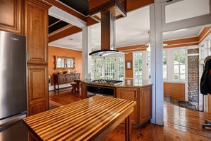 A kitchen with wooden cabinets, a stainless steel refrigerator, a gas stove, and a large window.