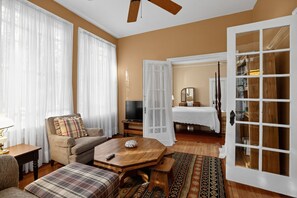 A living room with a sofa, armchair, coffee table, and a television.