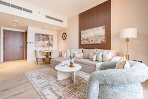 A modern living room with a sofa, armchair, coffee table, and a dining area with chairs and a table. - Majestic Hajar Mountain Views 1BR and Beach Access, Near Khorfakkan Amphitheatre (Khor Fakkan)