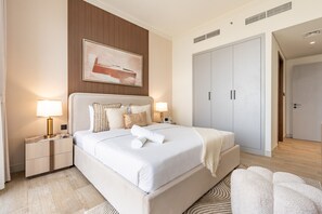 Une chambre d’hôtel moderne avec un grand lit, des lampes de chevet, une tête de lit ornée d’un tableau et une armoire.