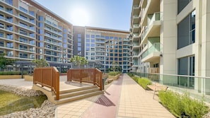 A modern residential building with multiple balconies, a paved walkway, and a small water feature. - Majestic Hajar Mountain Views 1BR and Beach Access, Near Khorfakkan Amphitheatre (Khor Fakkan)