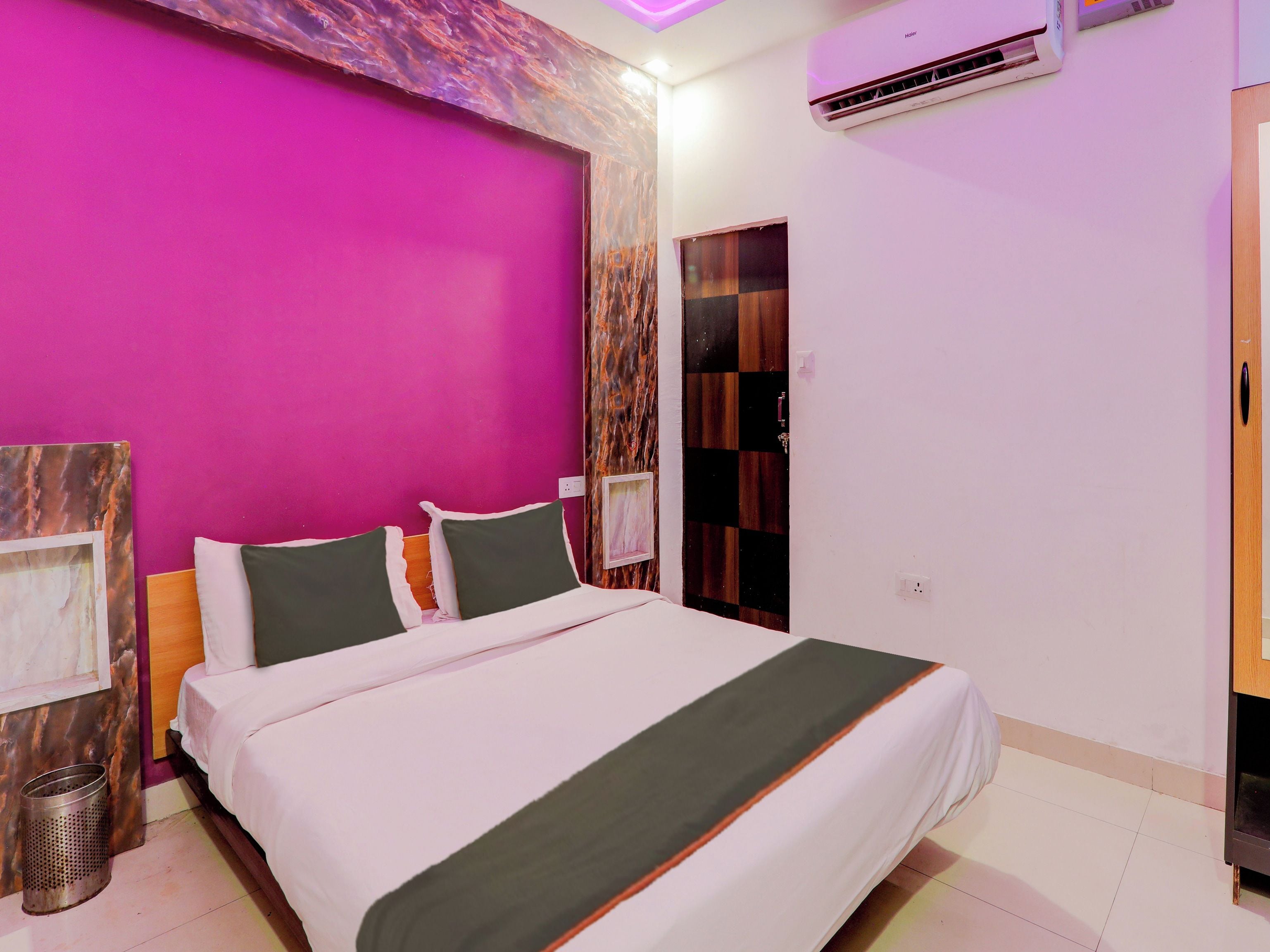 A hotel room with a bed, a wall-mounted air conditioner, and a door with a checkered pattern.
