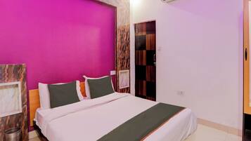 A hotel room with a bed, a wall-mounted air conditioner, and a door with a checkered pattern.