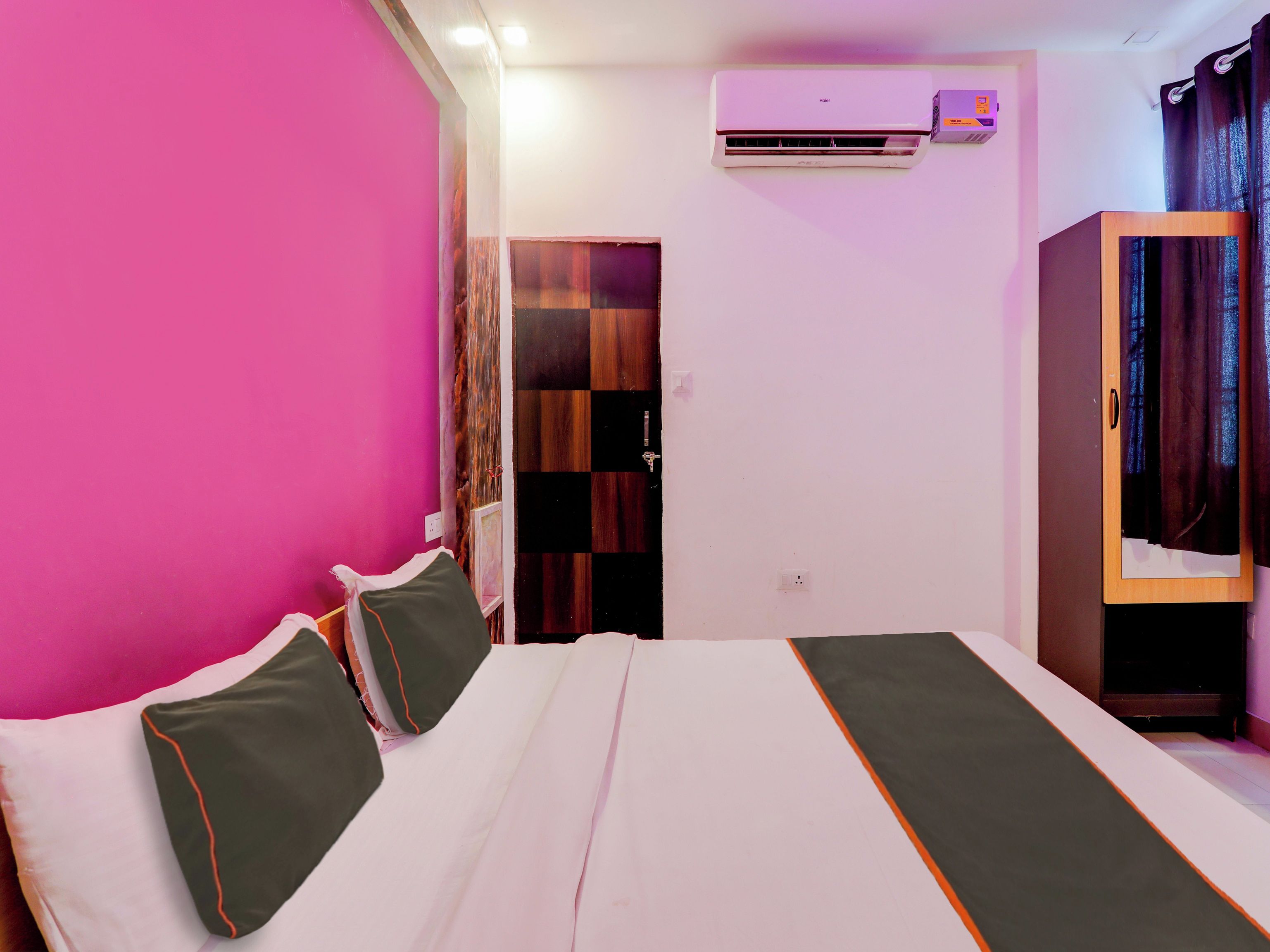 Een hotelkamer met een bed, een airconditioning, een kledingkast en een deur naar een andere kamer.