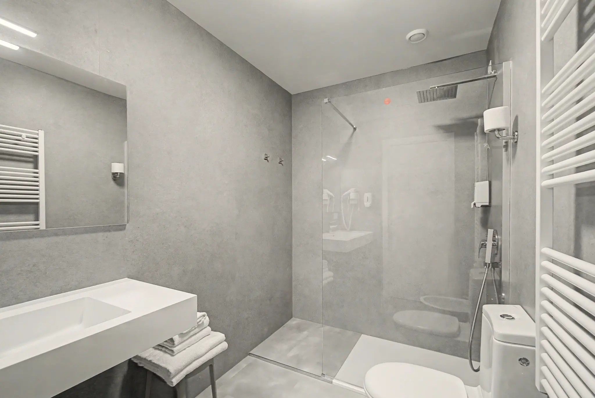 Un baño moderno con ducha envuelta en vidrio, un lavabo blanco y un inodoro.
