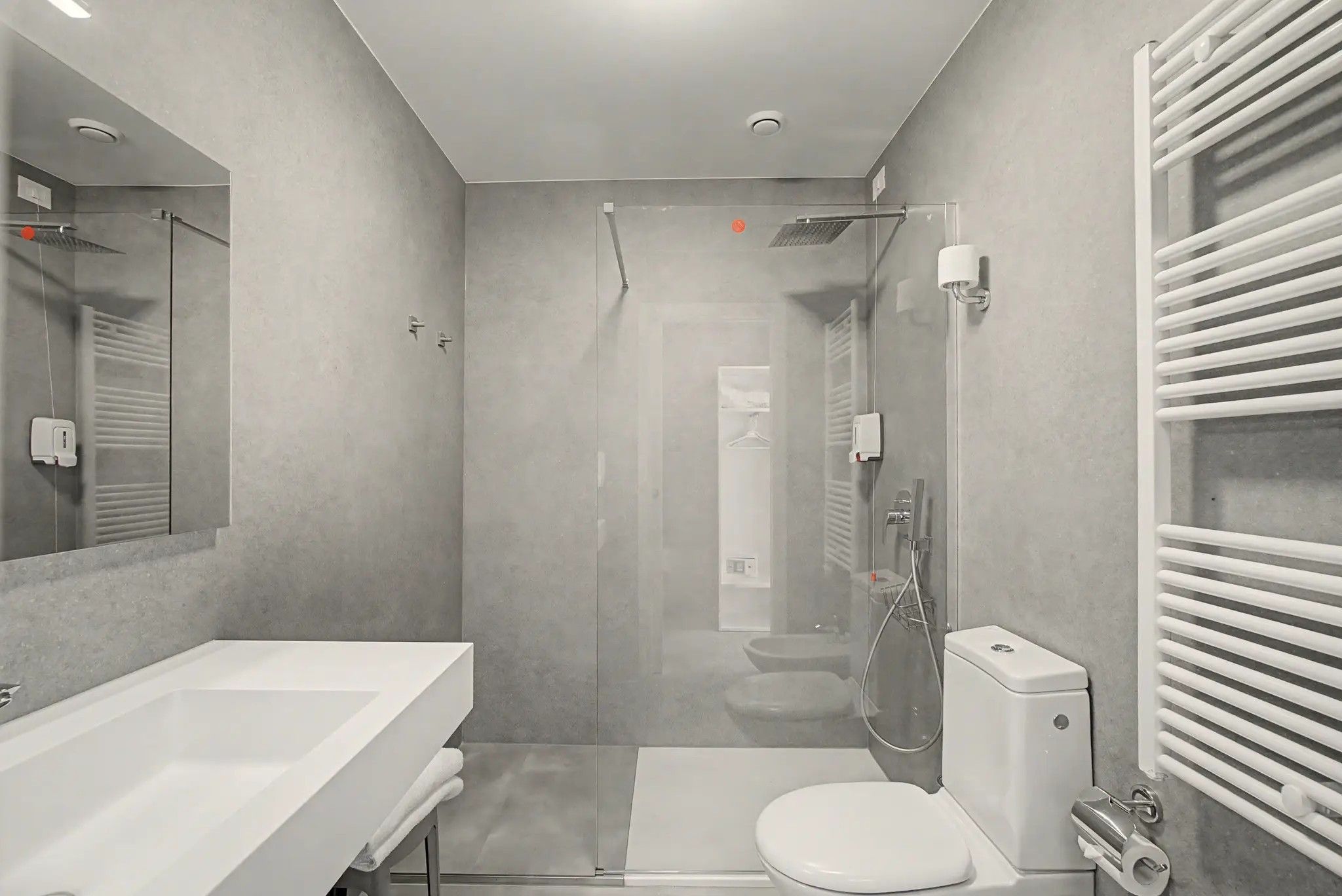 Une salle de bain moderne avec une douche à parois de verre, des toilettes blanches et un grand lavabo.
