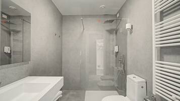Une salle de bain moderne avec une douche à parois de verre, des toilettes blanches et un grand lavabo.