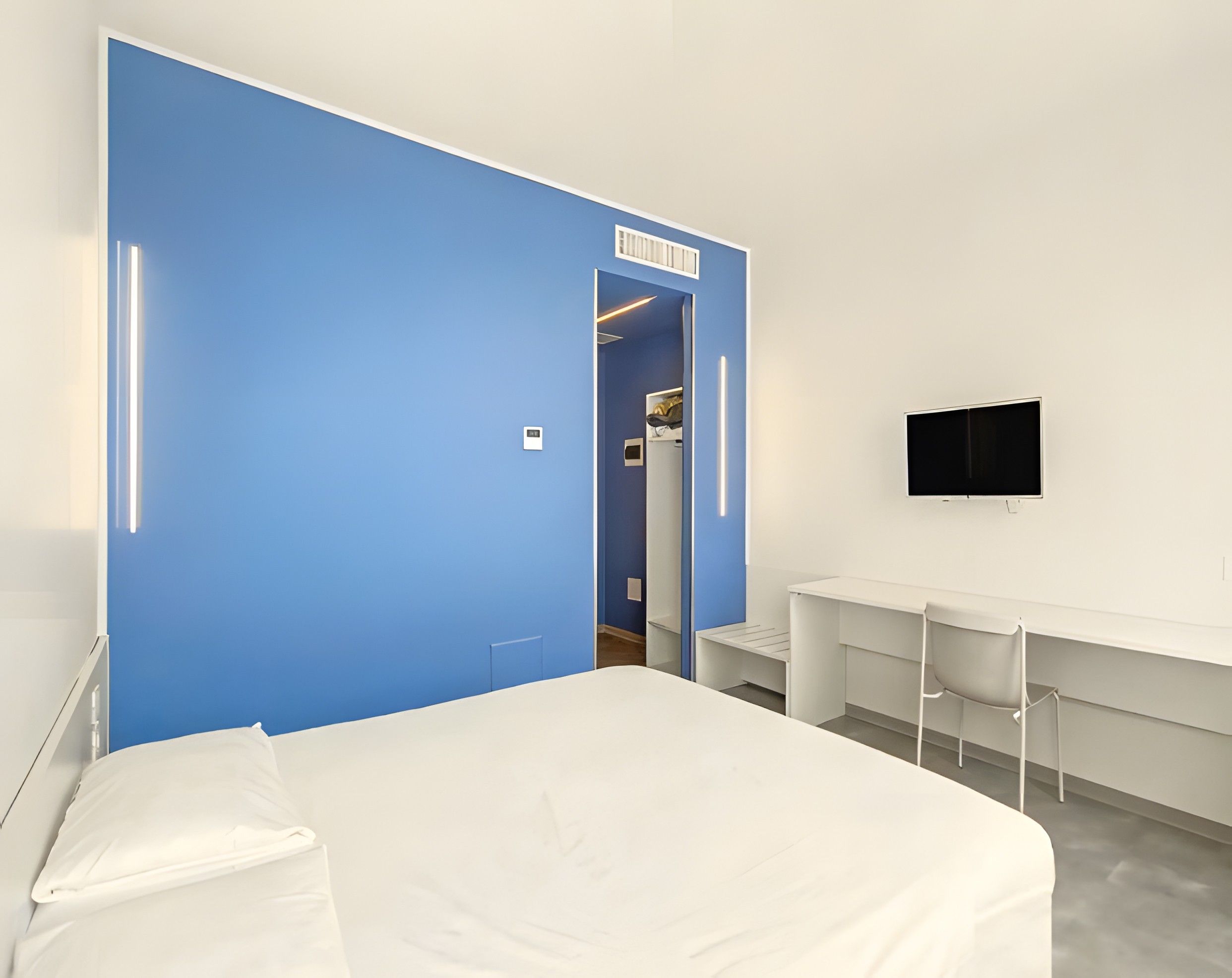 Une chambre d’hôtel avec un grand lit, une armoire, un bureau et une télévision.