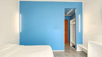A modern hotel room with a large bed, a blue accent wall, and a walk-in closet.