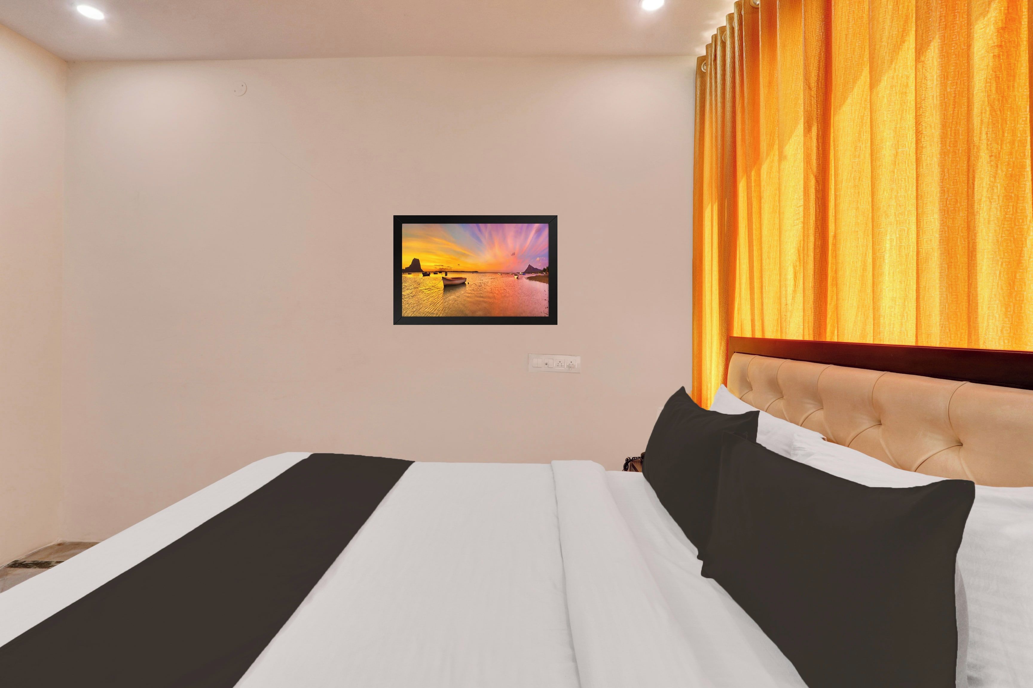 A hotel room with a bed, a headboard, a wall-mounted picture, and a window with curtains.