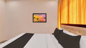 A hotel room with a bed, a headboard, a wall-mounted picture, and a window with curtains.