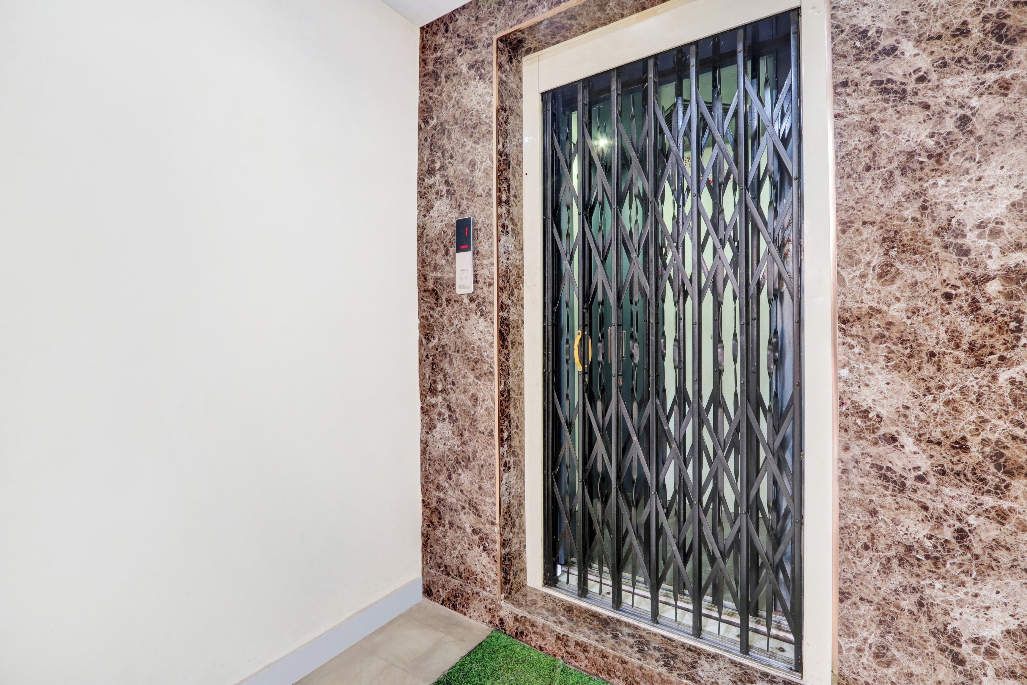 A room with a marble wall, a window with a metal grille, and a small indoor plant.