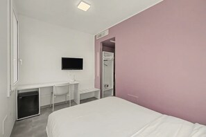 Ein Hotelzimmer mit einem Bett, einem Schreibtisch mit Stuhl, einem Fernseher und einem begehbaren Kleiderschrank.