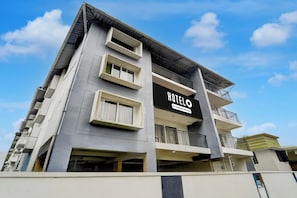 A multi-story hotel with a prominent sign indicating it is company-serviced. - Hotel O Karyavattom Formerly Viswam (Thiruvananthapuram)