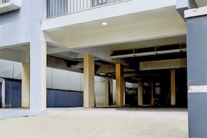 An underground parking garage with concrete pillars and a flat ceiling. - Hotel O Karyavattom Formerly Viswam (Thiruvananthapuram)