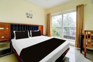 Quarto de hotel com uma cama grande, cabeceira de madeira, varanda com vista para palmeiras e janela com cortinas.