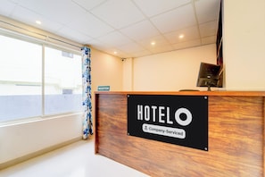 Balcão de recepção de hotel com placa indicando ser um hotel de serviço corporativo.