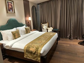 A hotel room with a large bed, a chair, a small table, and a curtain.