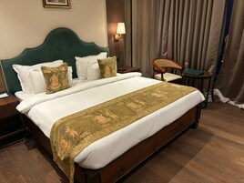A hotel room with a large bed, a nightstand, a chair, and a lamp.