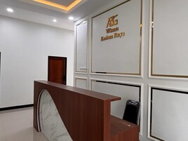 Un mostrador de recepción con encimera de mármol, mostrador de madera y una silla negra. La pared de fondo tiene un letrero con letras doradas.