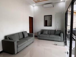 A modern living room with two grey sofas, a large mirror, and a glass door leading outside.
