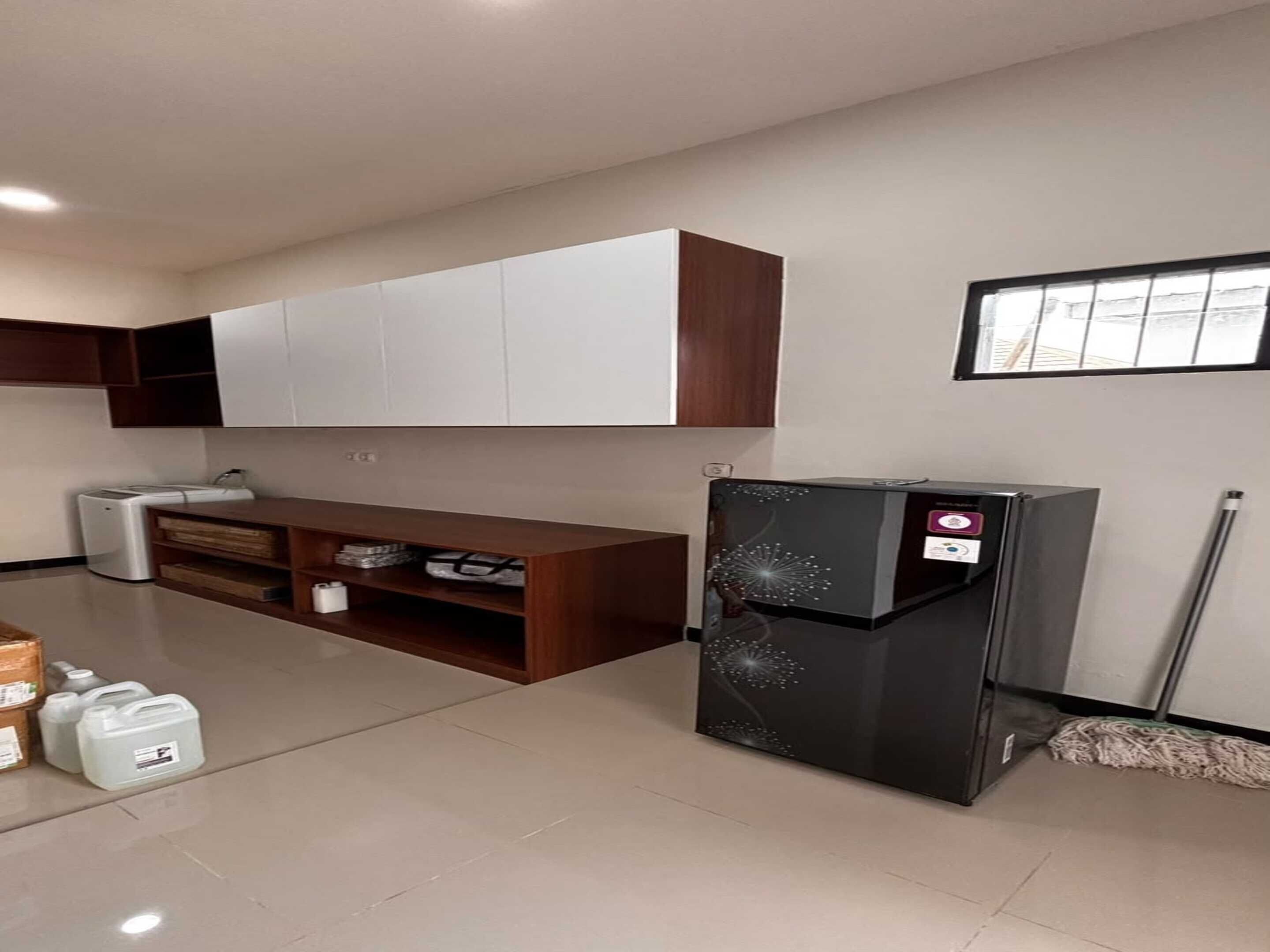 Una cocina moderna con armarios blancos, un refrigerador negro y un ventanal con barrotes.
