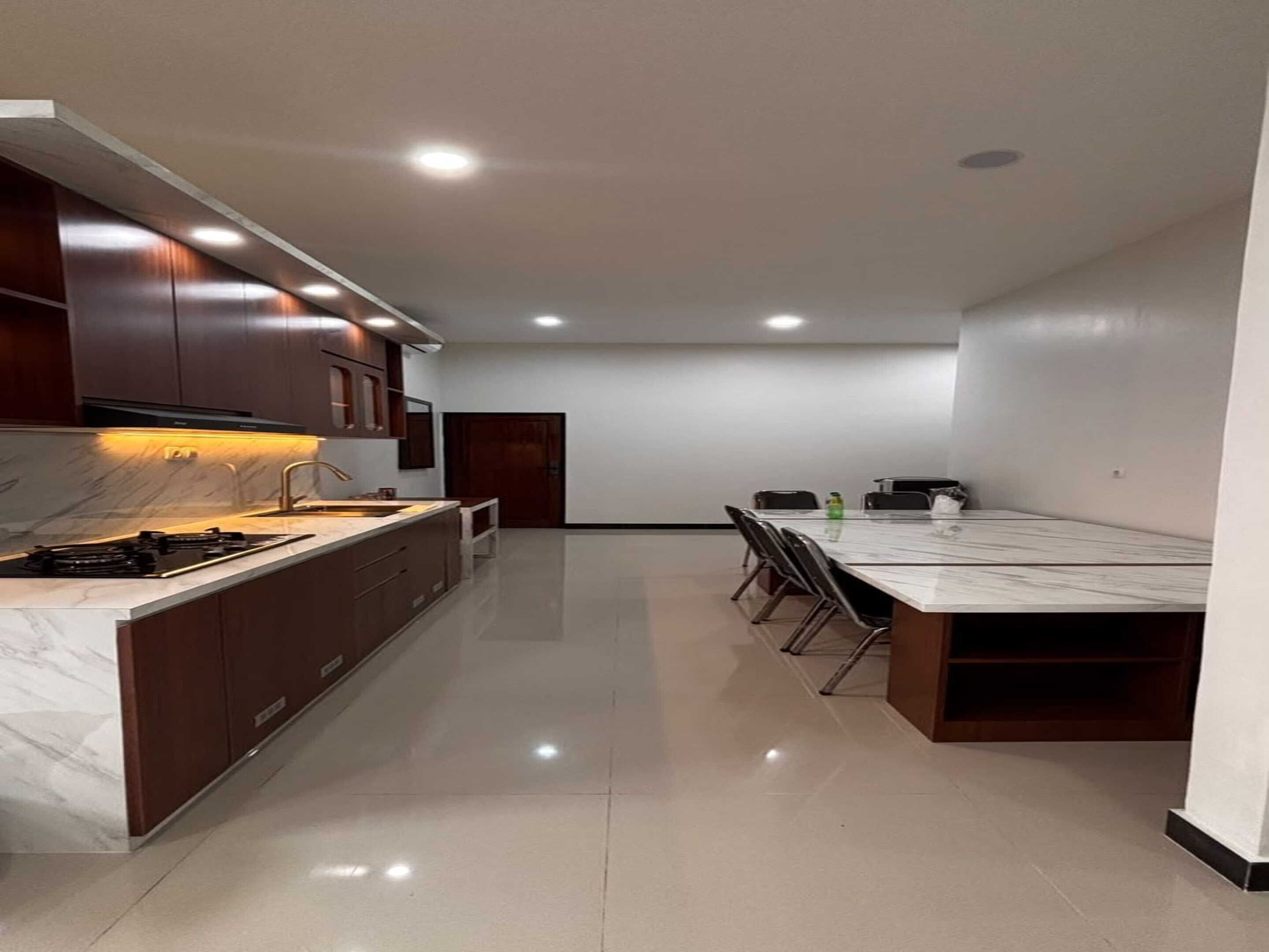 Una cocina moderna con encimera de mármol, armarios de madera oscura y un comedor con una mesa grande y sillas.