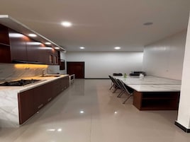Una cocina moderna con encimera de mármol, armarios de madera oscura y un comedor con una mesa grande y sillas.