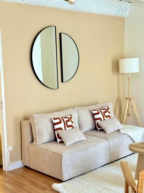 A beige sofa with striped cushions and a round mirror on the wall. - Bright 2-Bedroom Apartment with a Sunny Balcony—Heart of Old Toulon (Toulon)