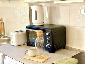 A kitchen with a toaster, a microwave, and a bottle on the counter. - Bright 2-Bedroom Apartment with a Sunny Balcony—Heart of Old Toulon (Toulon)