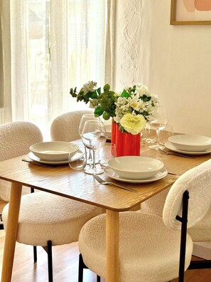 A dining table set for four with white plates, glasses, and a red vase with white flowers. - Bright 2-Bedroom Apartment with a Sunny Balcony—Heart of Old Toulon (Toulon)