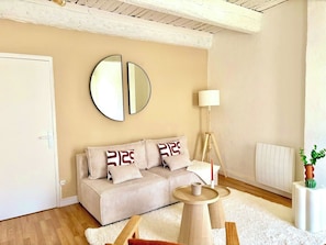 A living room with a sofa, a round mirror, a lamp, a radiator, and a potted plant. - Bright 2-Bedroom Apartment with a Sunny Balcony—Heart of Old Toulon (Toulon)