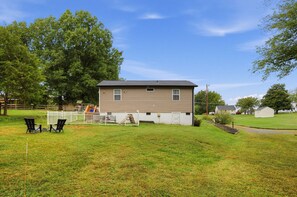 A single-story house with a fenced yard, a small shed, and a play area with a swing set. - Paws & Relax | Fredericksburg Home with Fire Pit (Fredericksburg)